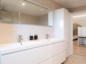 a white bathroom with a sink and a mirror at De Golfbreker in Middelkerke +65 photos