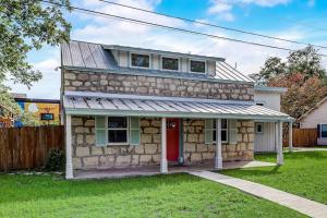 a stone house with a red door at Downtown 2-Story Home with Enclosed Backyard, Patio, Pool, Playground, W/D, AC in Fredericksburg