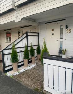 a white house with potted plants on the front porch at 2 Bedroom Apartment Tiller in Trondheim