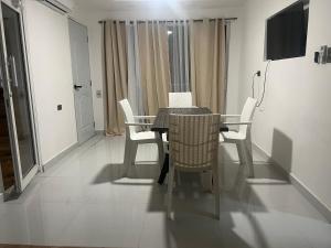 a dining room table with white chairs and a television at Santa Barbara River house in Santo Domingo