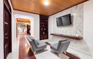 a living room with two chairs and a tv on a wall at Urban House in Florencia