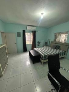 a bedroom with a bed and a desk and chairs at Ricardo's Rest Spot in Curatoe Hill