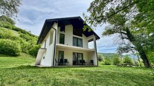 a small white house with a black roof at RiverHouse Tošinović in Šipovo