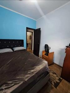 a bedroom with a large bed and a blue wall at Pousada Praia Grande in Mongaguá