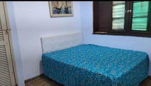 a bed in a room with a blue cover at Pousada Praia Grande in Mongaguá