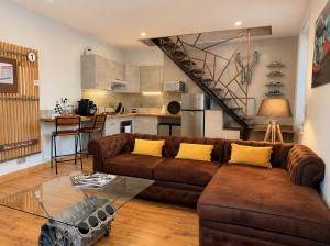 a living room with a brown couch and a kitchen at Suite Le Mans 70 in Pusey