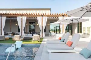 a pool with white chairs and umbrellas next to a house at Luxury 1bedroom 1bath Tech Hub in Austin