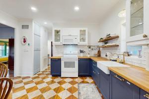 a kitchen with blue cabinets and a checkered floor at Blue Haus with Hot Tub, Shuffleboard, EV Charger - Walk to Town & Wineries in Johnson City