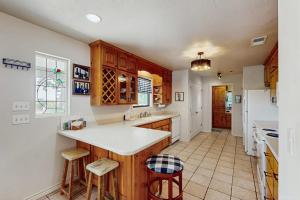 a kitchen with wooden cabinets and a white refrigerator at Idyllic Home with Firepit, Gazebo, Patio, & Amazing Deck Views - Dog-Friendly in Fredericksburg