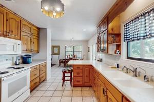 a large kitchen with wooden cabinets and white appliances at Idyllic Home with Firepit, Gazebo, Patio, & Amazing Deck Views - Dog-Friendly in Fredericksburg
