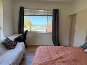 a room with two beds and a window with a desk at 1 Bedroom Flat with Private Kitchen & Ensuite in Bulli