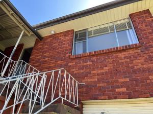 a brick house with a white metal staircase on it at 1 Bedroom Flat with Private Kitchen & Ensuite in Bulli +6 photos