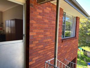 a brick building with a door and a window at 1 Bedroom Flat with Private Kitchen & Ensuite in Bulli