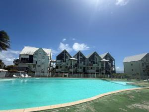a swimming pool in front of some apartment buildings at Pieds dans l eau Piscine Calme Appartement Althéa in Le Gosier