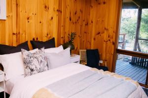 a bedroom with a white bed and a wooden wall at A charming escape from everyday life in Aireys Inlet