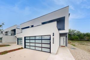 a white house with a large garage at Modern Lago Vista Home with Balcony, Patio, Gas Grill, WIFI, and AC in Lago Vista