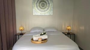 a bed with a towel and a candle on it at Pieds dans l eau Piscine Calme Appartement Althéa in Le Gosier
