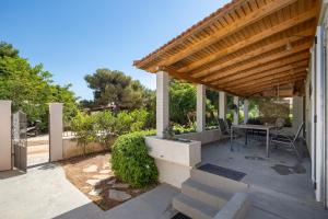 a patio with a wooden pergola and a table at Chill Coast House in Nisís Áyios Nikólaos