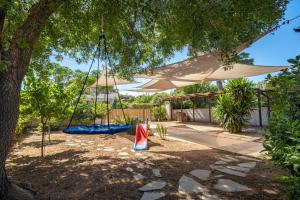 a swing under a tree with an umbrella at Chill Coast House in Nisís Áyios Nikólaos