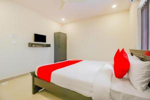 a bedroom with a bed with red and white pillows at SPOT ON Pnd Complex in Hyderabad