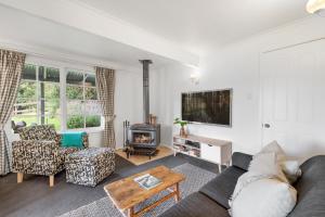 a living room with a couch and a fireplace at Alcheringa Cottage Amazing Location with views in Kangaroo Valley