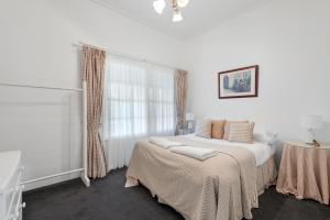 a white bedroom with a bed and a window at Alcheringa Cottage Amazing Location with views in Kangaroo Valley