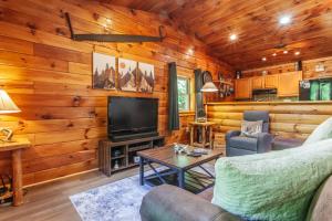 a living room with wooden walls and a flat screen tv at Edge View Chalet in Bryson City