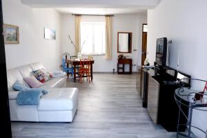 a living room with a white couch and a tv at Elpidios Galatro Terme in Galatro