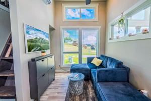 a living room with a blue couch and windows at Modern Tiny Home with Loft, Kitchen, Cozy Patio and Shared Pools, Great Location in Fredericksburg