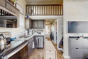 a kitchen with wooden floors and white cabinets at Modern Tiny Home with Loft, Kitchen, Cozy Patio and Shared Pools, Great Location in Fredericksburg