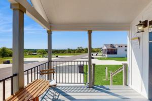 a porch with a bench and a view of a field at Modern Tiny Home with Loft, Kitchen, Cozy Patio and Shared Pools, Great Location in Fredericksburg