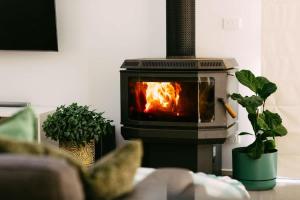 a stove with a fire in a living room with plants at Perfect Beachside Escape - Walk Everywhere in Anglesea