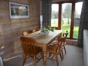 a wooden table and chairs in a room with windows at Charming Cottage in Romney Marsh Britain with Wooden Deck in Ivychurch