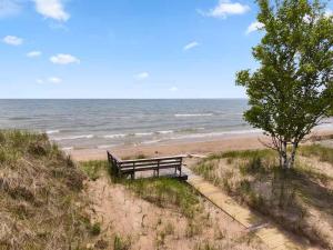 a bench sitting on the beach near the ocean at Dune Alright by Simple Life Rentals in Baileys Harbor