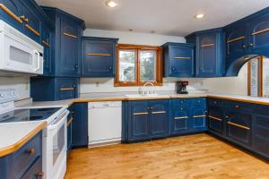a blue kitchen with white appliances and blue cabinets at Dune Alright by Simple Life Rentals in Baileys Harbor +28 photos