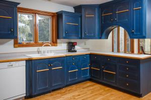 a kitchen with blue cabinets and a sink at Dune Alright by Simple Life Rentals in Baileys Harbor