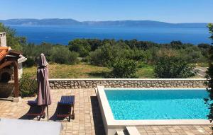 a swimming pool with two chairs and an umbrella at Studio Apartment In Labin in Labin