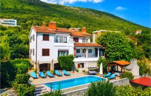 a house with a swimming pool in front of a mountain at Apartment Labin Ravni in Labin