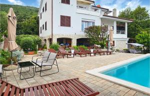 a patio with chairs and a swimming pool and a house at Apartment Labin Ravni in Labin