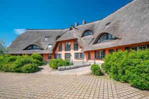 a large house with a thatched roof and a driveway at Strandnest in Dierhagen