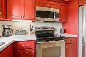 a kitchen with red cabinets and a stove and a microwave at Upper Deck by Simple Life Rentals in Sturgeon Bay +13 photos