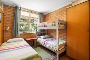 two bunk beds in a room with a brick wall at Saltwinds - Steps to Beach & Lighthouse in Aireys Inlet