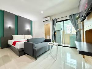 a bedroom with a bed and a couch and a table at Chalong - Studio Service Apartment - Phoomjai in Ban Klang