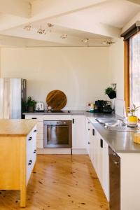 a kitchen with white cabinets and a wooden floor at The Angle House - Aireys Inlet in Aireys Inlet