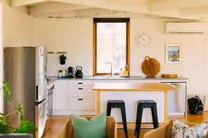 a kitchen with a counter with stools and a sink at The Angle House - Aireys Inlet in Aireys Inlet