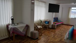 a room with a table and chairs and a tv at Casa jardín Roqui in Puno