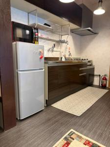 a kitchen with a white refrigerator with a microwave at 民泊利休 in Sakai +16 photos