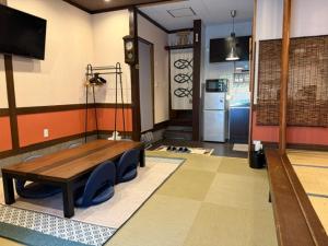 a room with a table and chairs and a kitchen at 民泊利休 in Sakai