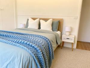 a bedroom with a bed with a blue blanket on it at Sunny Coastal Retreat in Anglesea