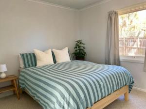 a bedroom with a striped bed with a window at Sunny Coastal Retreat in Anglesea